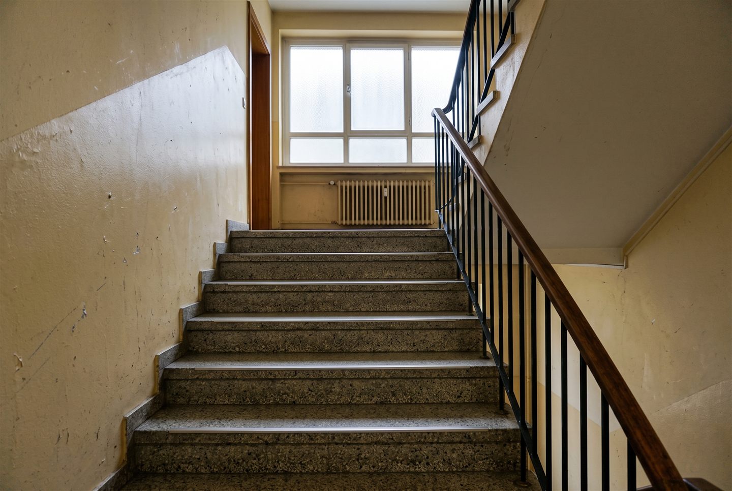 Leeres Treppenhaus von unten, der Handlauf führt die Stufen hinauf